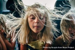 Three blond siblings sitting in vehicle with wind in their hair 5r7V74