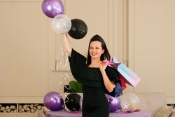 Woman in dress holding balloons and posing at party