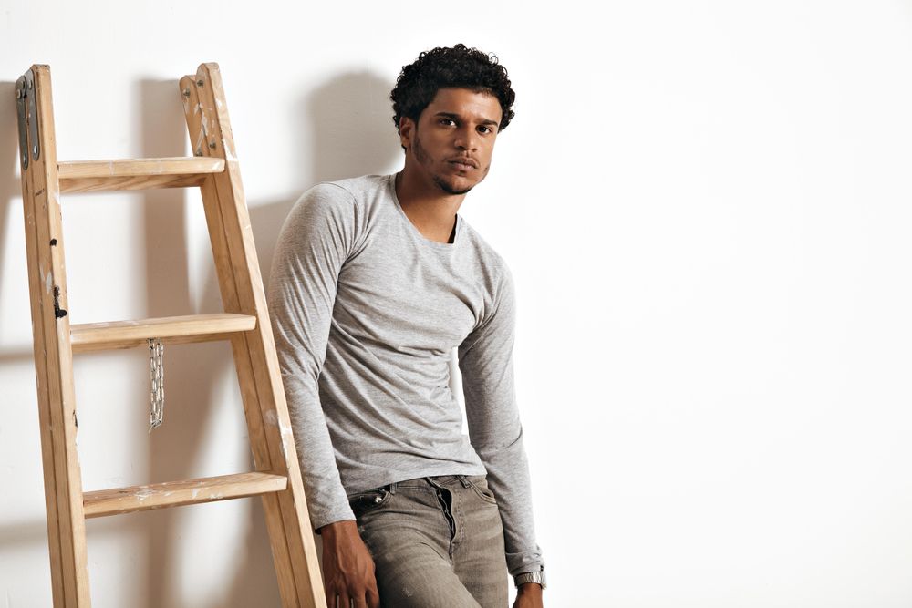 Man leaning against wall next to ladder