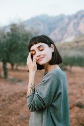 Woman with eyes closed in beautiful park with hills and olive trees