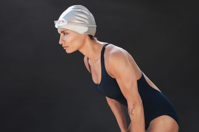 Side view of woman leaning over in swimsuit and cap
