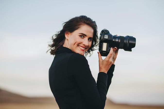 Freelance photographer looking over shoulder while holding camera in hand