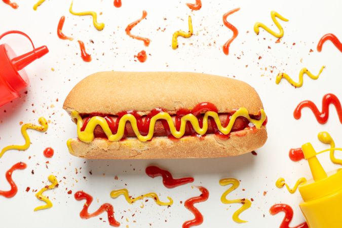 Hot dog and sauces on plain background, top view