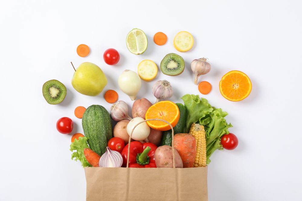 Flat lay with paper bag, vegetables and fruits on background, copy space