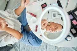 Smiling woman applying cosmetic mask with brush
