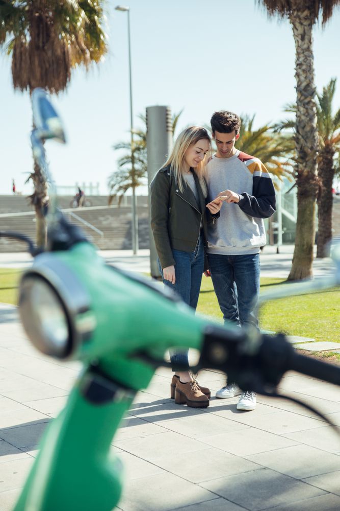 Woman and man standing and looking at mobile phone near too bike