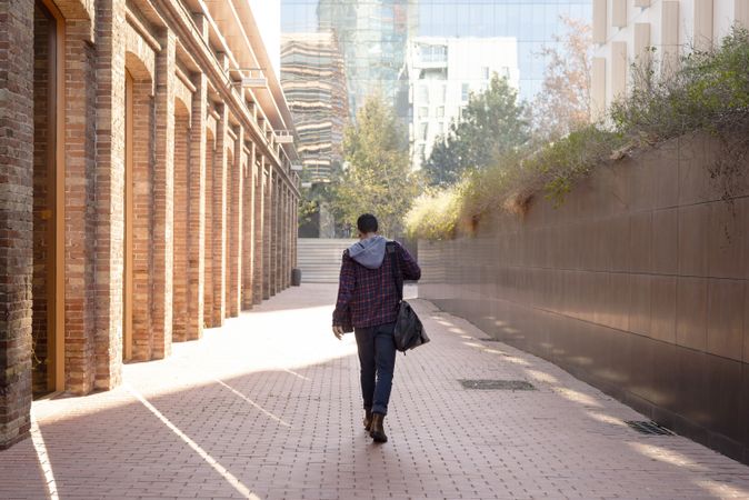 Rear view of a man with shoulder bag walking through the city