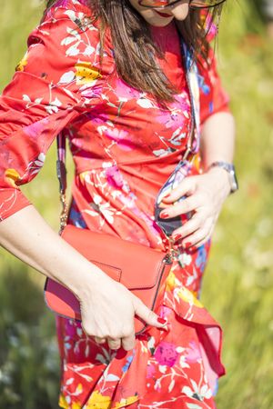 Crop female with bag standing in summer field