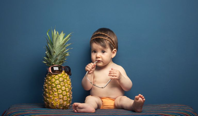 Happy baby playing with a pineapple