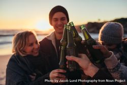 Young people toasting with beer bottles on beach 0WjjOb