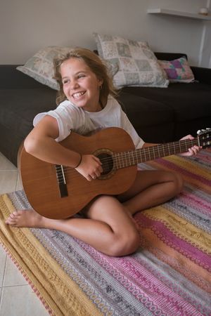 Barefoot girl playing guitar at home