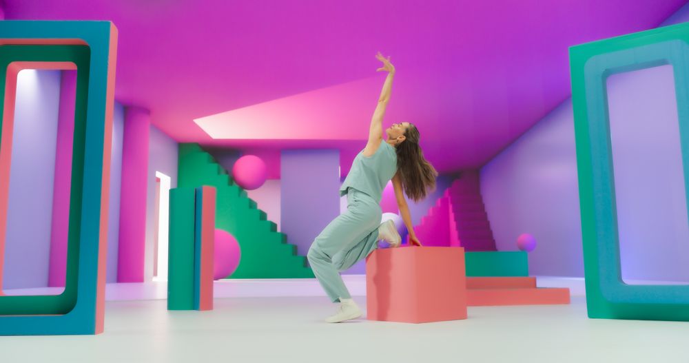 Woman with Bright Makeup Dancing Energetically in Colorful Geometric Abstract Environment. Creative Young Female Happily Performing Modern Dance Choreography in a Studio