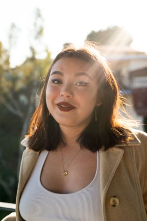 Close up of young woman with classic makeup looking at camera with sun rays