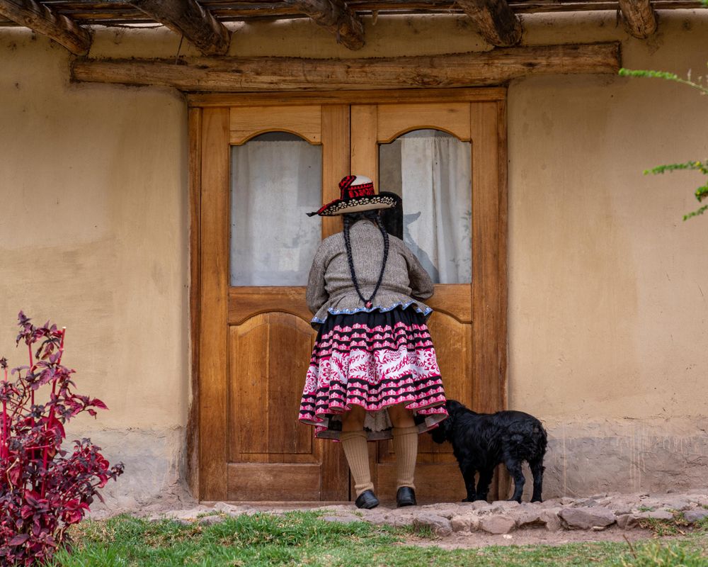Backside of woman in colorful skirt standing in front of closed door
