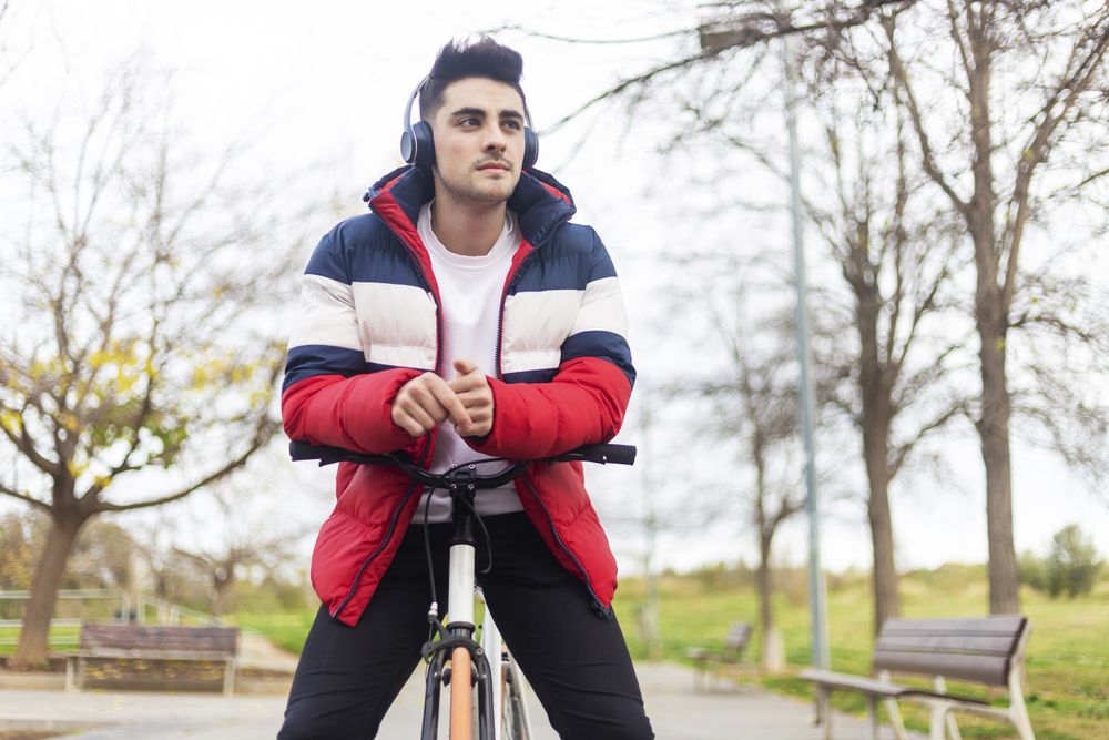 Handsome cool young man enjoying a bicycle ride and listening to music on headphones