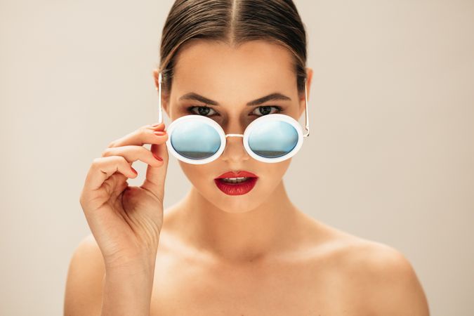 Portrait of fashion woman peeking over sunglasses