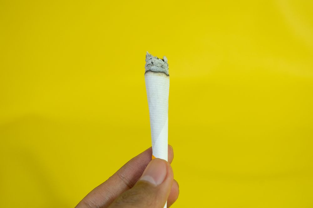 Side view of hand holding burning cigarette