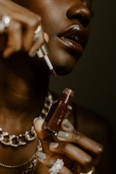 Woman holding bottle of brown lip-gloss