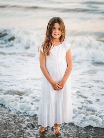 Smiling girl standing on seaside among waves