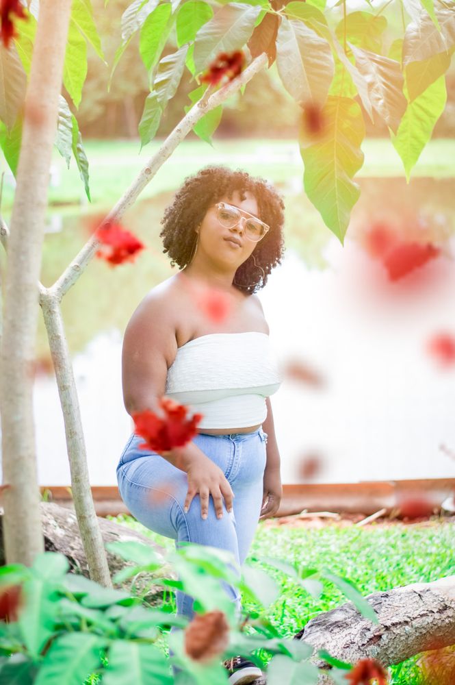 Woman in tube top and blue denim jeans standing on green grass field