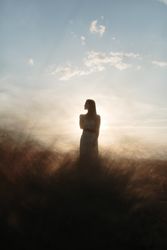 Young woman standing in an open field looking to the side
