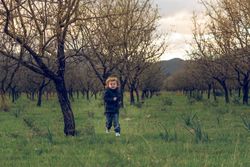 Boy running in grove with trees