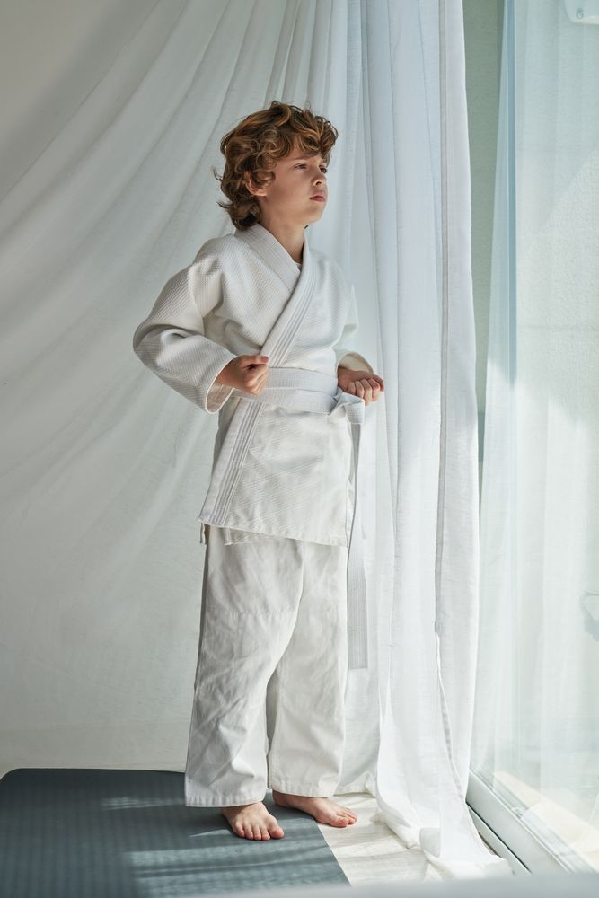 Pensive boy in kimono standing near window
