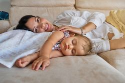 Mother and cute kid resting on sofa at home