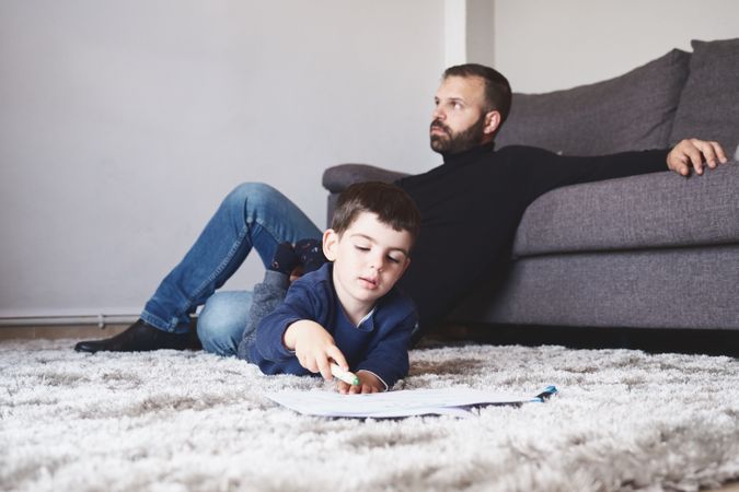 Son drawing on floor next to his father