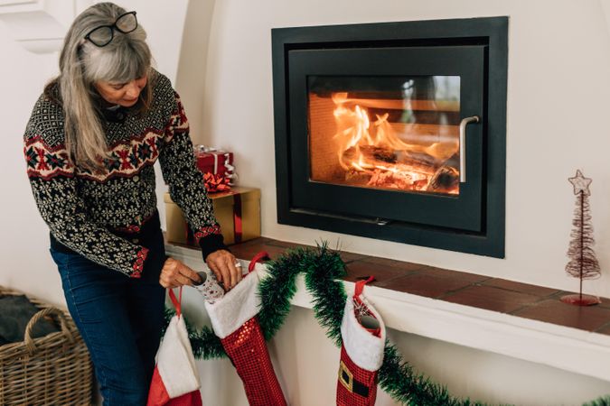Woman putting stuff in santa socks while decorating home for christmas