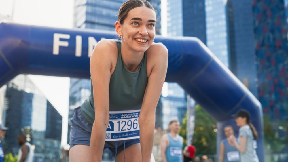 Portrait of a Happy Female City Marathon Runner Crossing the Finish Line and Celebrating her Victory.