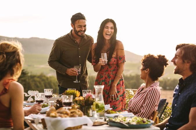 Smiling man and woman making an announcement during a dinner party outdoors