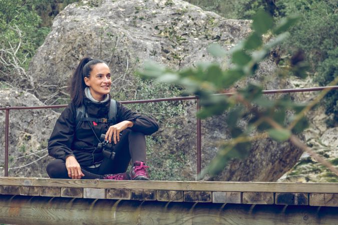 Happy female hiker relaxing on bridge during trekking in