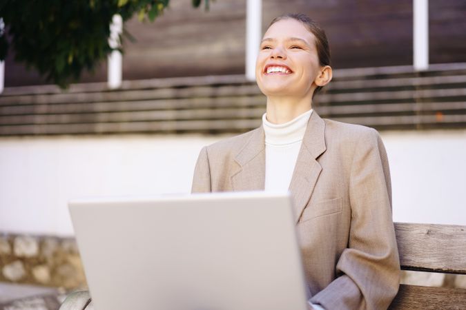 A Smiling Businesswoman is Enjoying Her Work on a Laptop While Sitting Outdoors in Nature