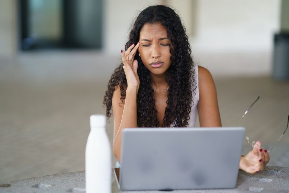 A Stressed Woman Struggling While Working on Laptop in Contemporary Modern Workspace