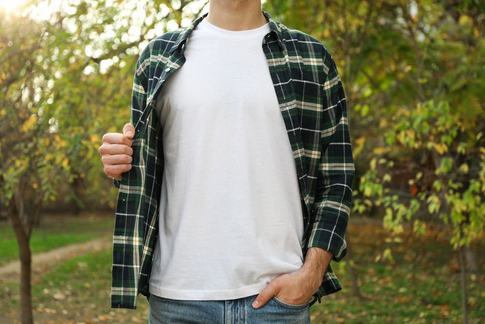 Men in t-shirt and checkered shirt in park, copy space