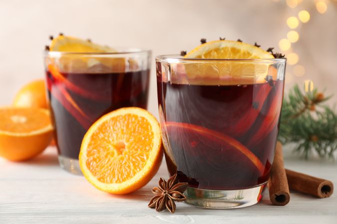 Glasses of tasty mulled wine with orange on wooden background, space for text