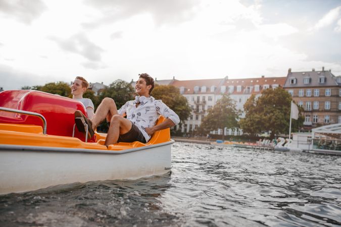 Outdoors shot of two young friends sitting in pedal boat