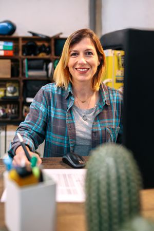 Portrait of smiling blonde young woman filling order forms for ecommerce shop.