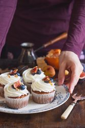 Oven baked cupcakes with cream frosting and fruit on top