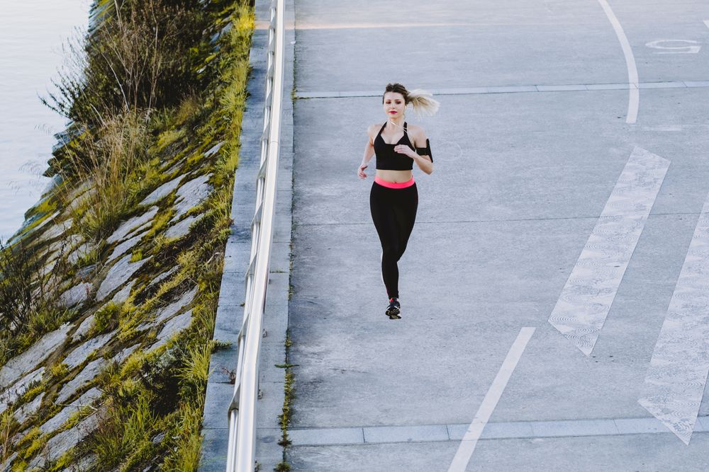 Woman running on embankment near water