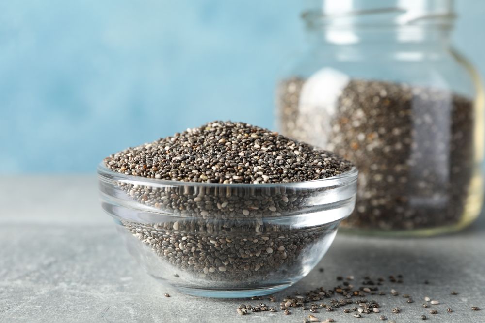 Glass tableware with seeds on grey table, space for text