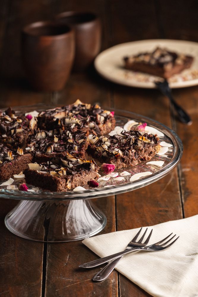 Tasty brown cake decorated with flakes on glass plate