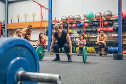Woman ready to do weightlifting while her gym mates cheering her on