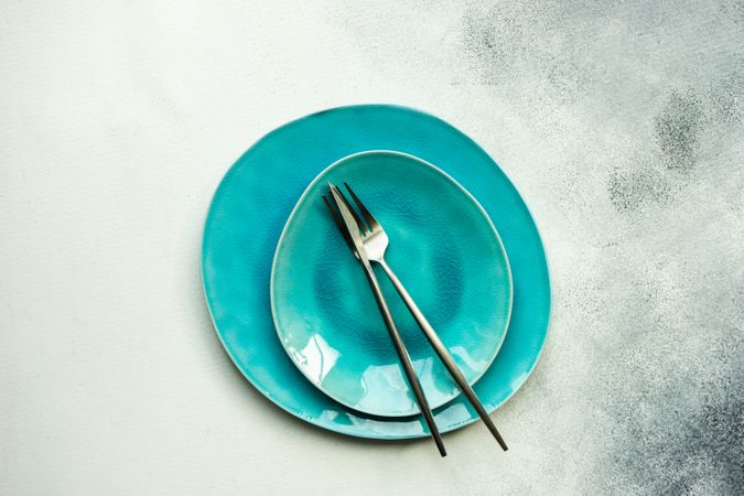 Top view of modern teal plates with silverware
