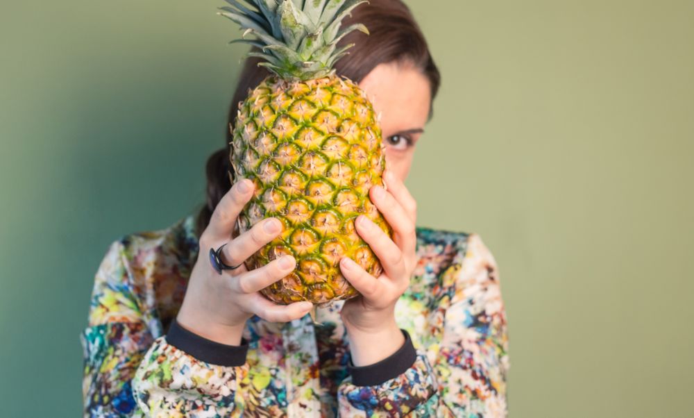 Woman holding pineapple in front of face