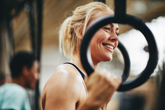 Blonde woman smiling at gymnastic rings