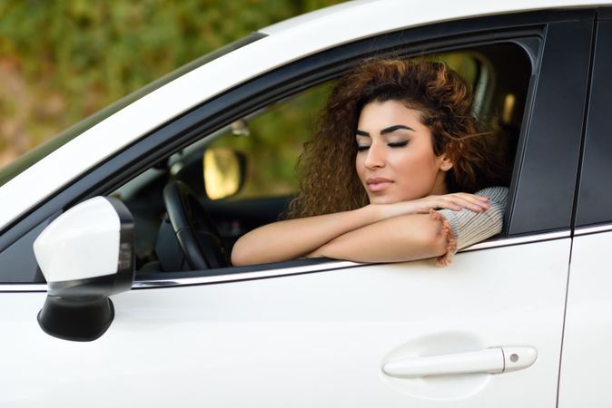 Female with curly hair leaning wistfully out driver’s window
