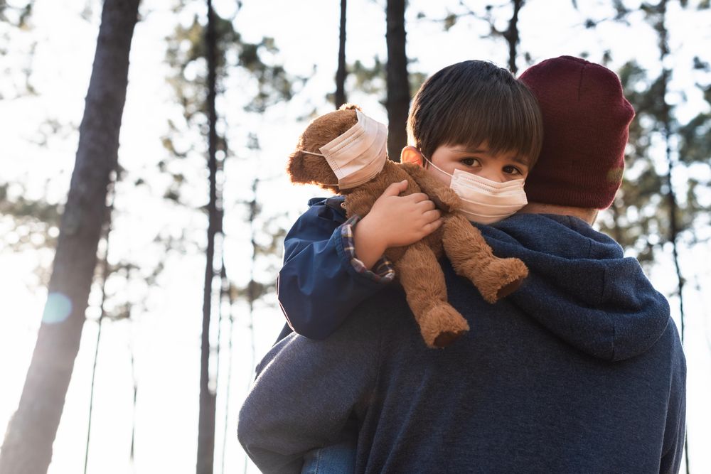 Man carrying a boy with facemask