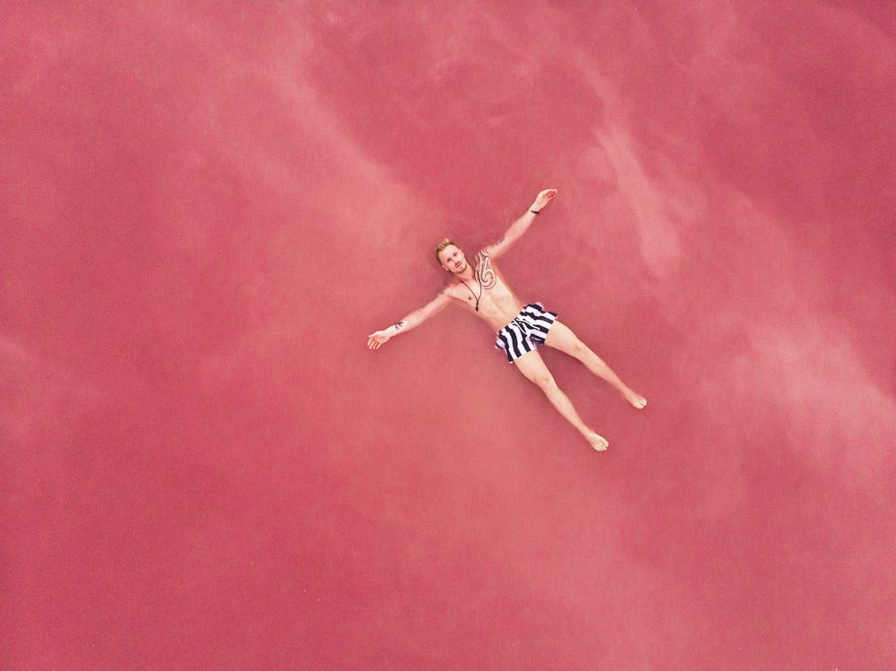 Carefree man on vacation delighting in pink water of lake